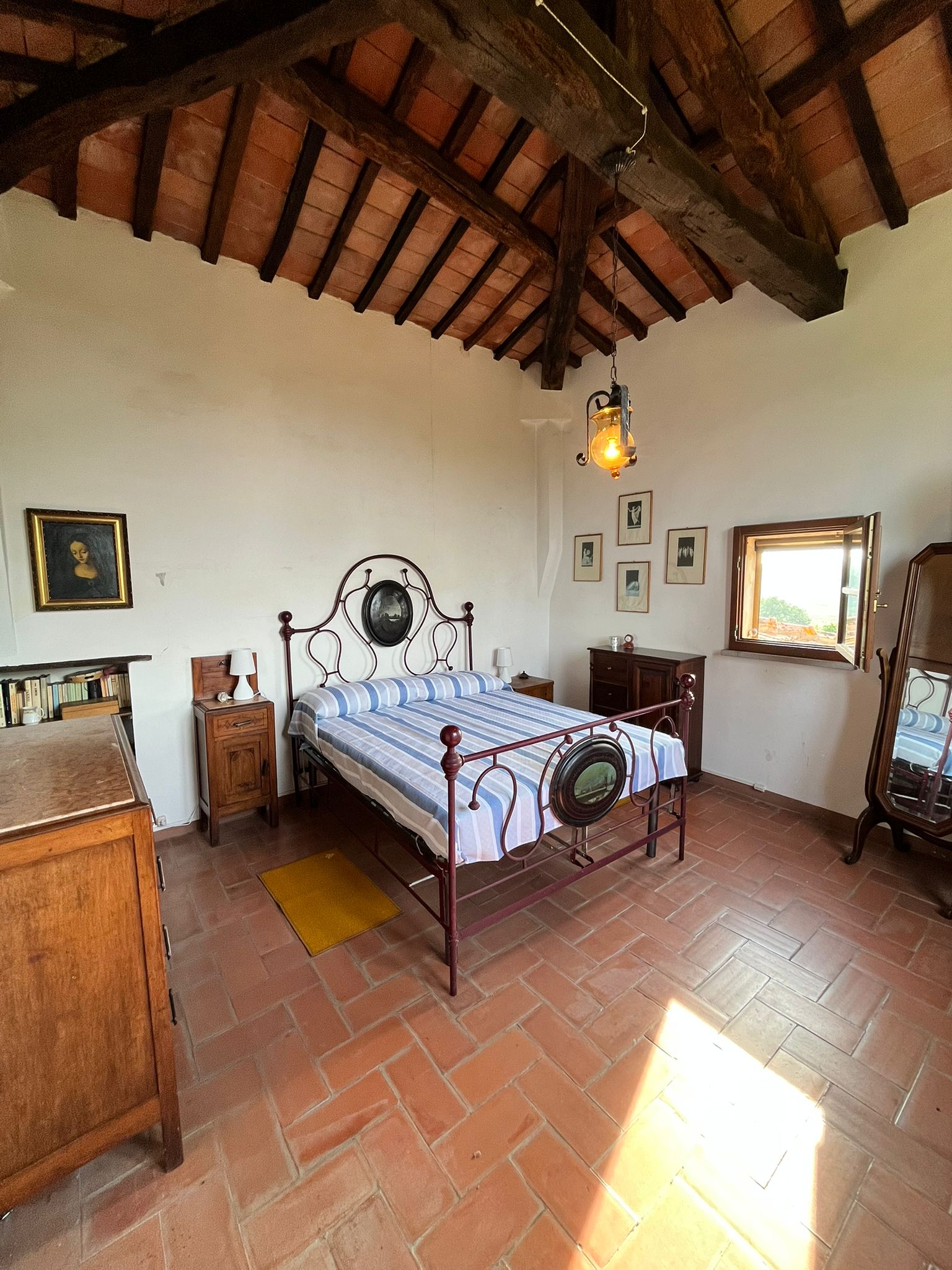 Camera La Torretta con letto in ferro battuto, travi a vista e pavimento in cotto