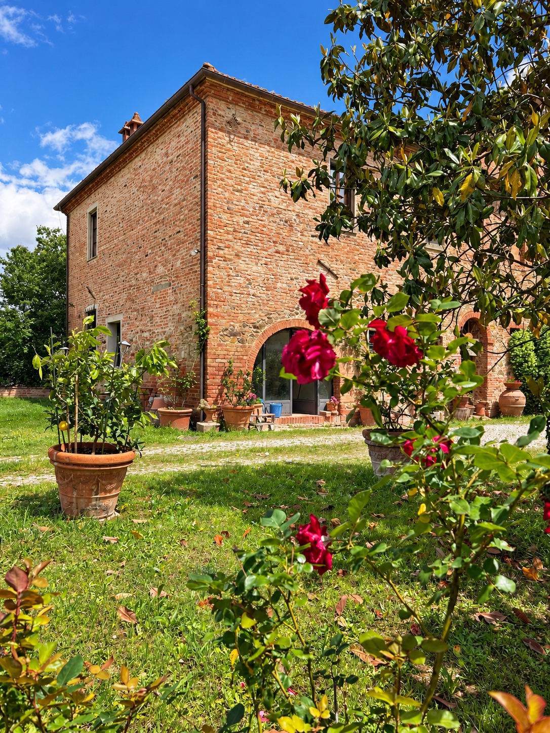 La casa colonica in mattoni vista dal giardino, tra le rose